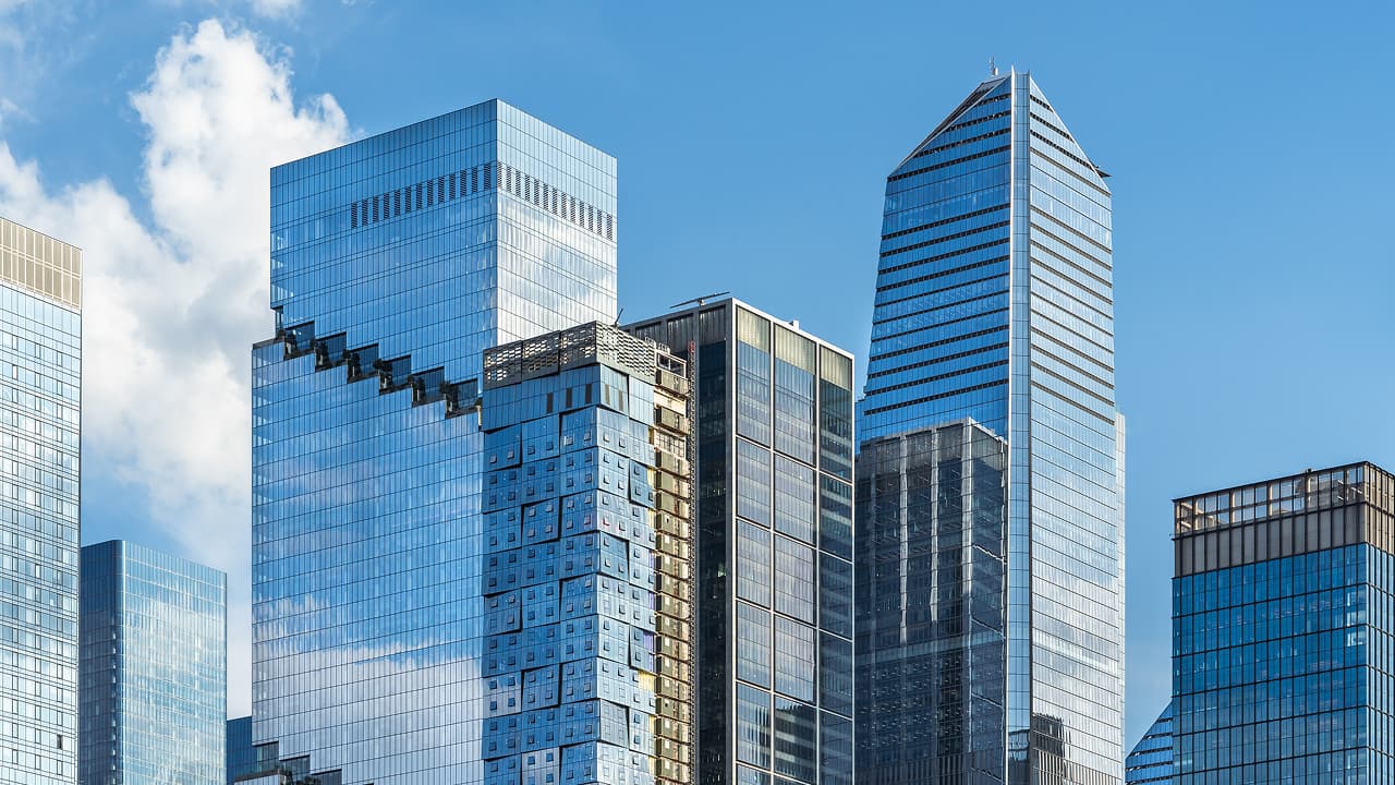 Buildings in a downtown area against a blue sky and a white cloud. 